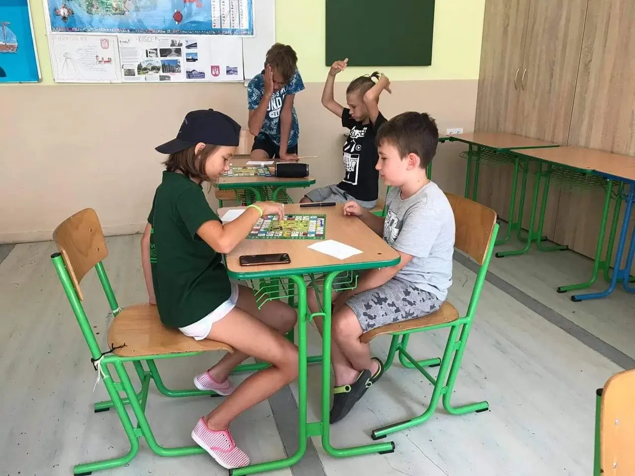 Štyri deti v školskej triede hrajú edukačnú hru Magické písmenká od Miaplay počas letnej výučby
