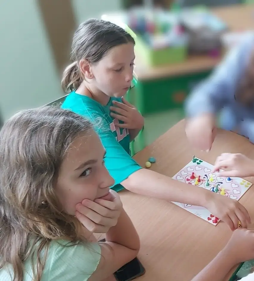 Dve žiačky sa sústredene hrajú miniatúrnu verziu hry Srdiečka od Miaplay pri školskej lavici
